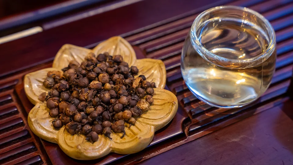Chén trà đã pha bên đĩa hoa chè khô trong bộ ảnh Cổ Nguyệt Trà